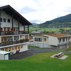 En bygning med en plen foran seg og en høyde i bakgrunnen