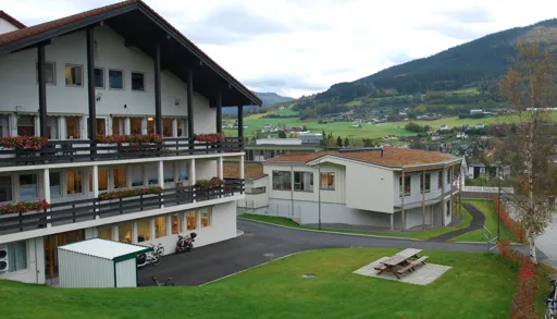 En bygning med en plen foran seg og en høyde i bakgrunnen